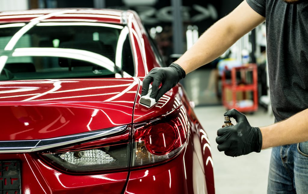 Red car being serviced for small dents and imperfections from damage like hail, rocks, or harsh conditions.